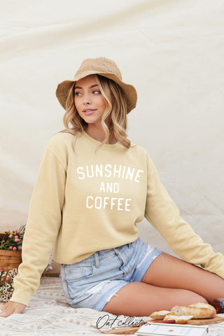 Woman wearing the light butter yellow sweatshirt with 'Sunshine and Coffee' text, sitting outdoors.